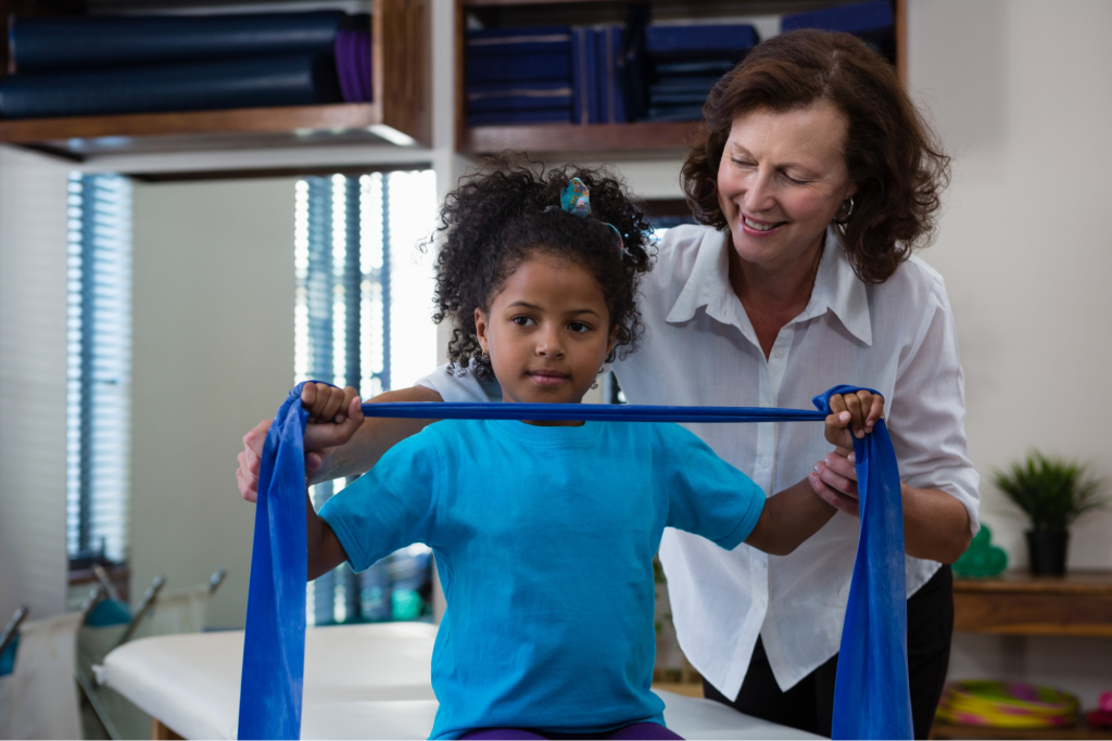 A little girl performs stretching exercises with a resistance band during physical therapy.