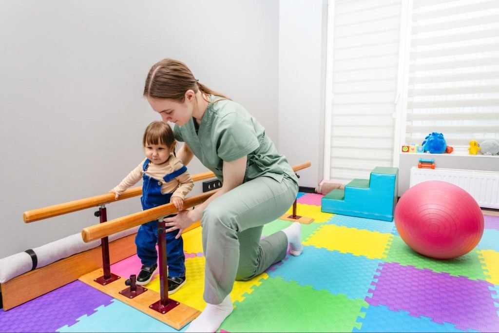 A physiotherapist assists a young girl with cerebral palsy in walking on a rehabilitation ramp during therapy.