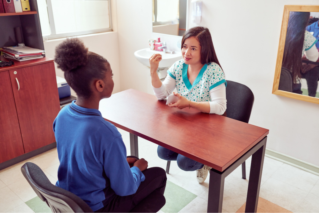 A speech therapist engaged in a one-on-one session with a young girl to support communication development.