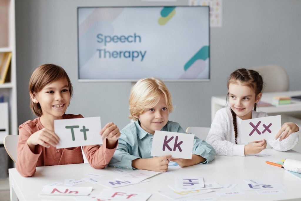 Kids in speech therapy hold flashcards with phonetic letters to practice sounds and articulation.