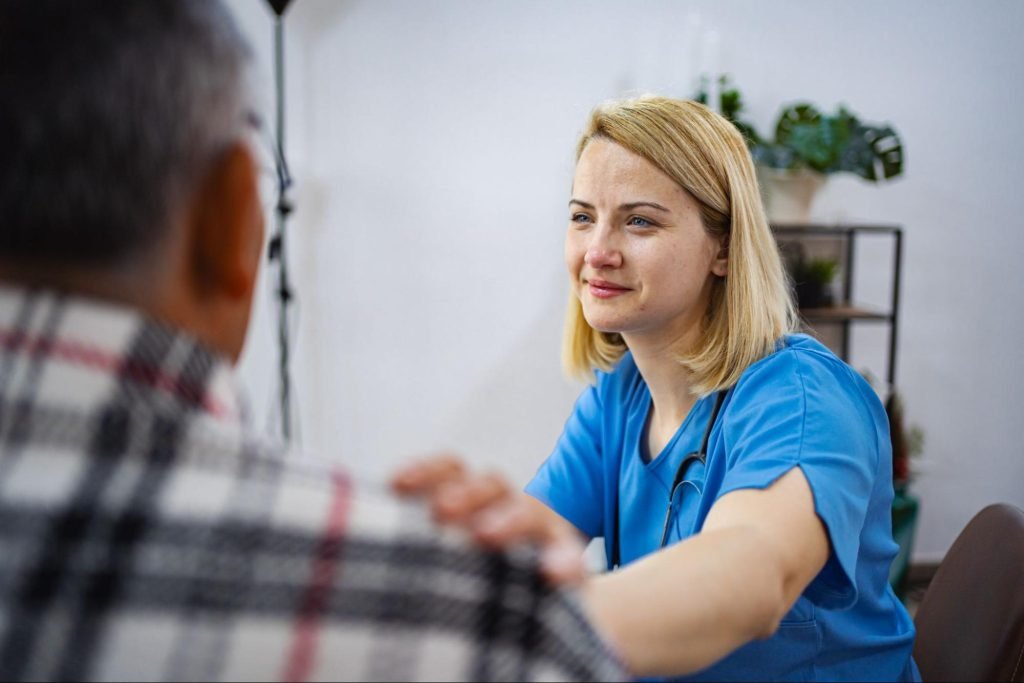 A nurse has her hand on a patient's shoulder for comfort.