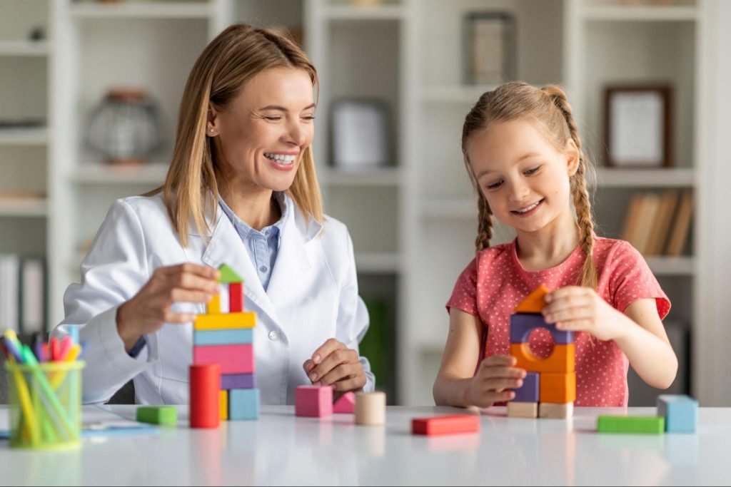 A child development specialist plays with wooden blocks with a young girl.