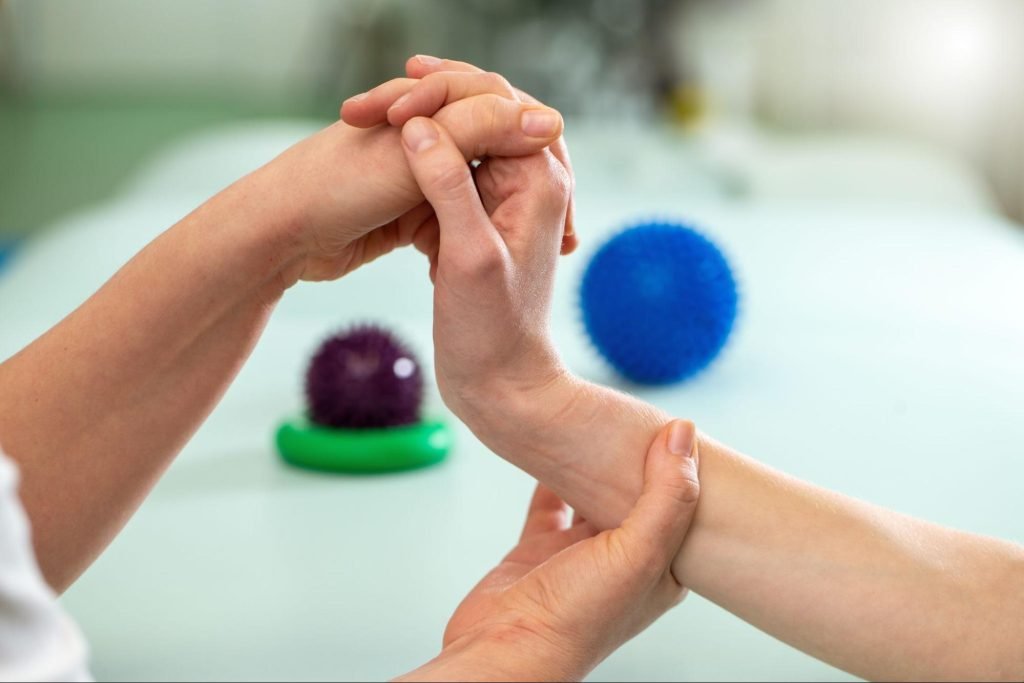 A doctor assists a patient in stretching their wrist.