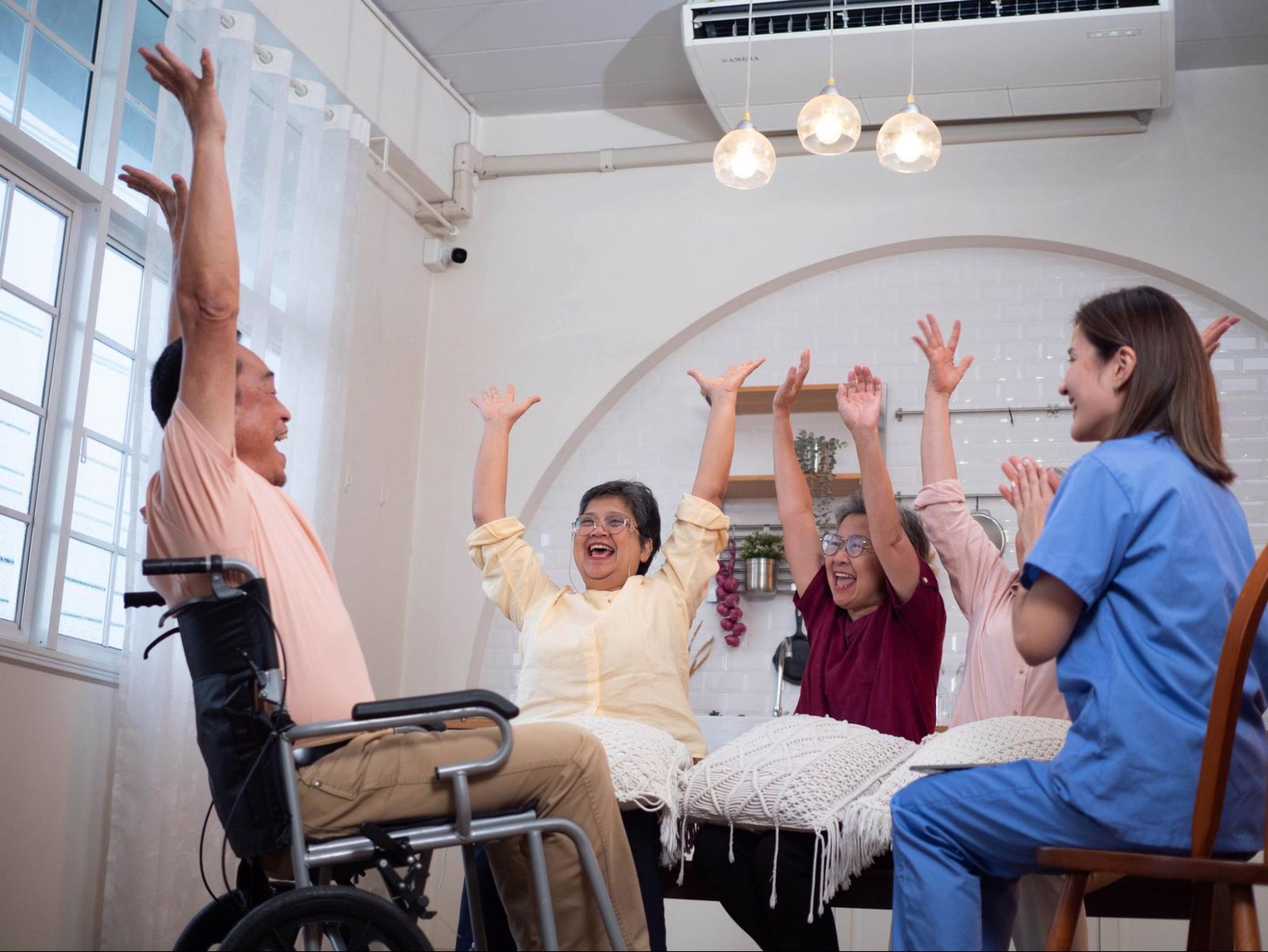 A nurse is sitting in a circle with elderly people who have their hands up in the air.