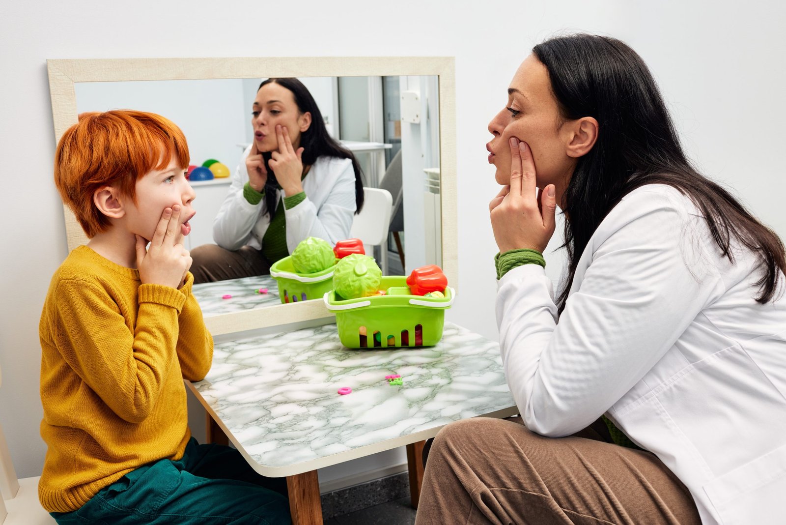 A pediatric speech therapist teaches a child how to form sounds with his mouth.