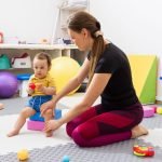 Physiotherapist guiding a young child with coordination difficulties through motor skill exercises 