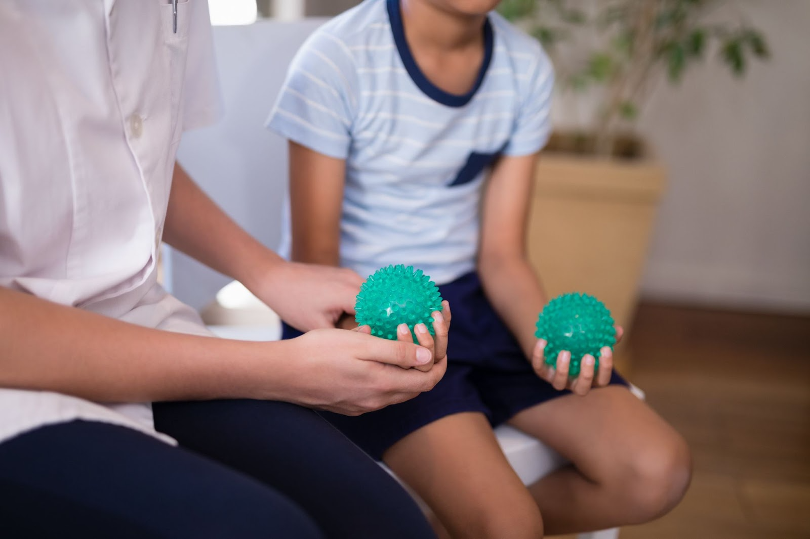 Occupational therapist guiding a young boy with stress balls to improve hand strength and coordination
