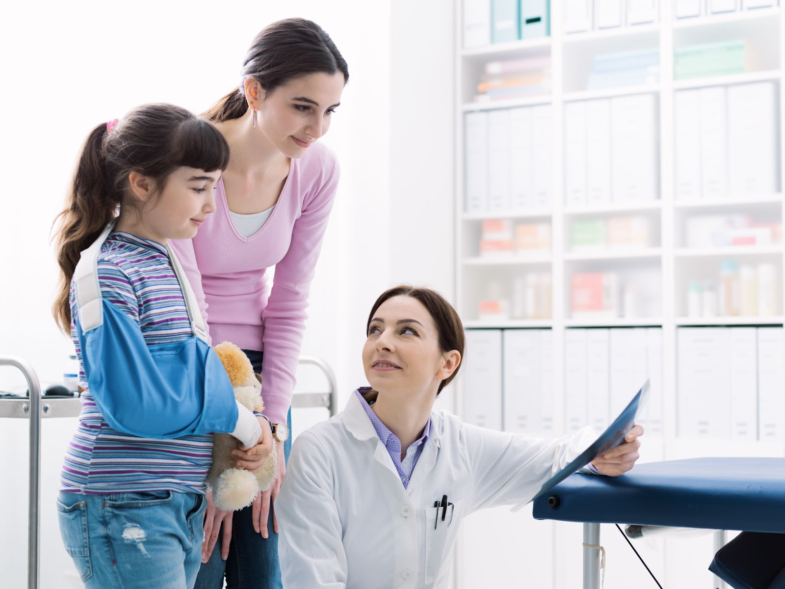 Rehab physician reviewing broken bone x-ray with child before starting physical therapy.